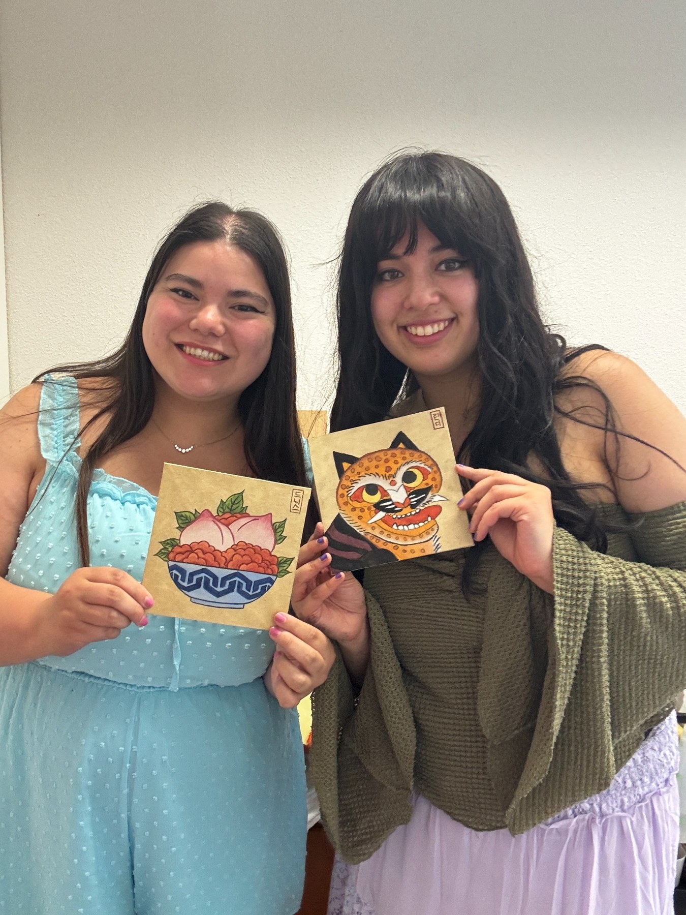 Two students smiling with finished Minhwa paintings